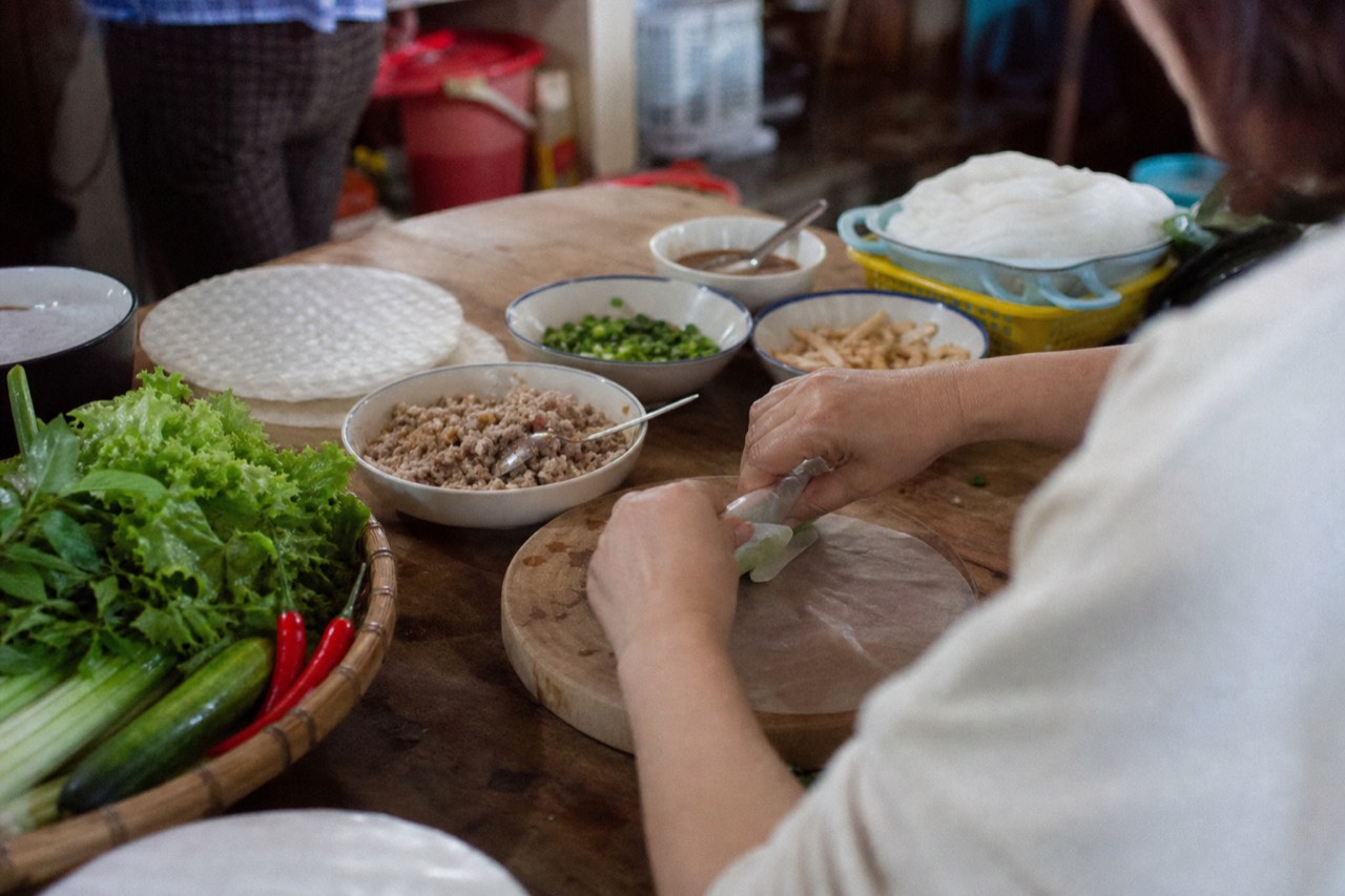 Fresh herbs, banana flower and market vegetables laid out on a Hanoi cooking class bench