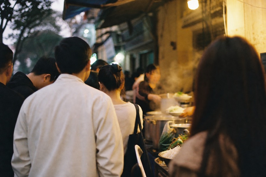 Small group tasting street food at a busy Hanoi Old Quarter stall