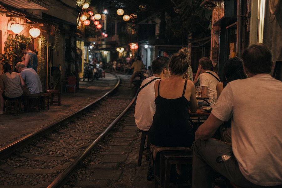 Evening food walk pausing at a Train Street cafe in Hanoi with drinks by the rails